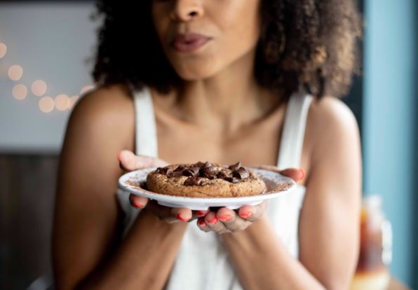 a woman hlding a plate with a large cookie